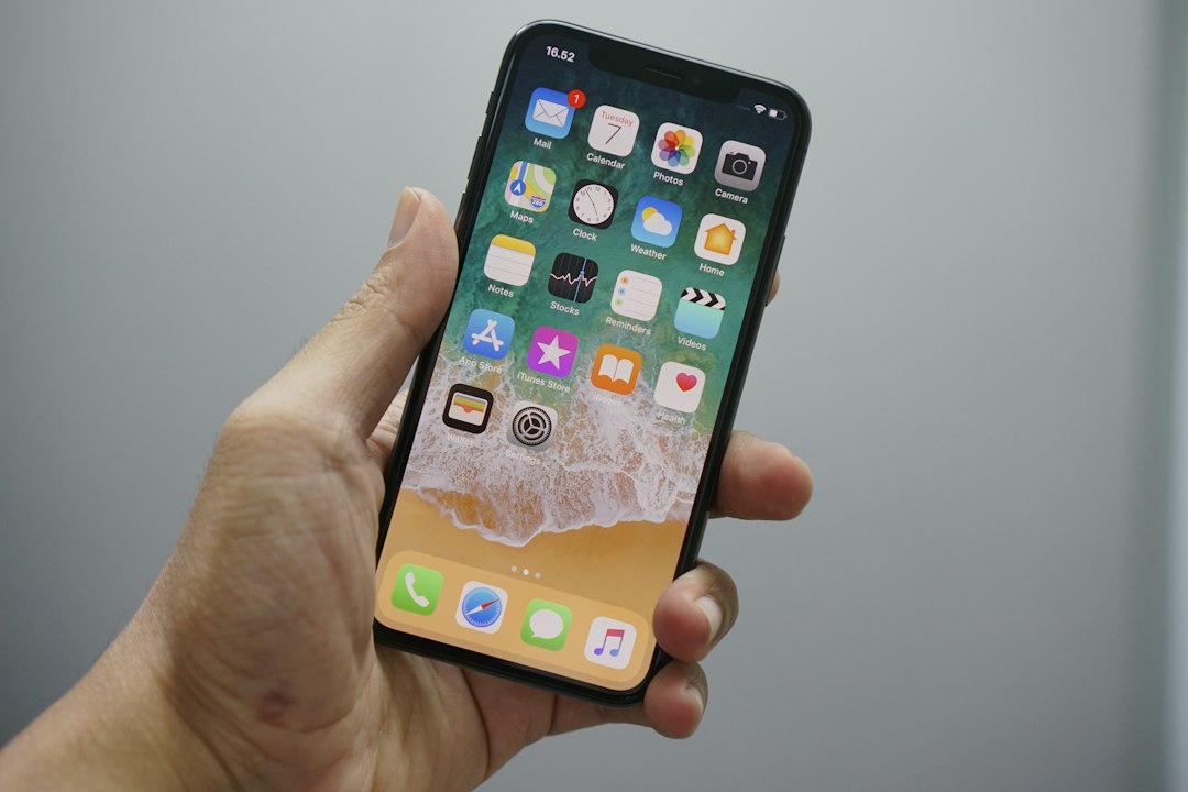Hand holding an iPhone, illustrating the Apple CoreGraphics zero-day.
