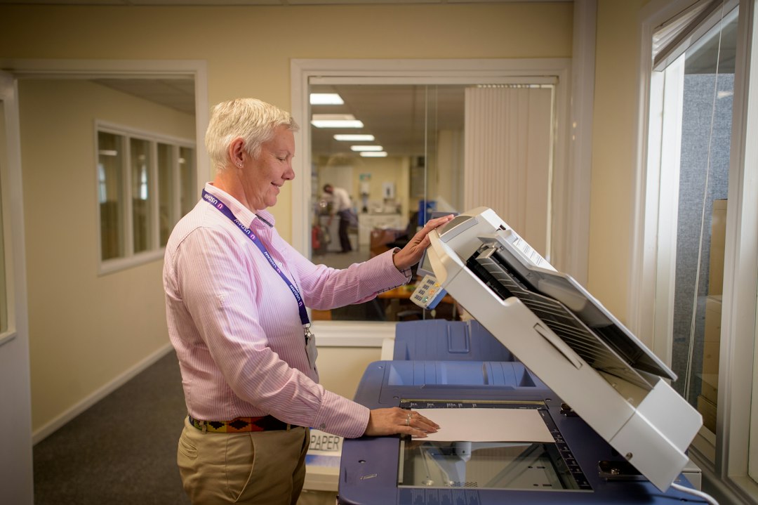 Office worker using a copier, illustrating PaperCut active exploitation.