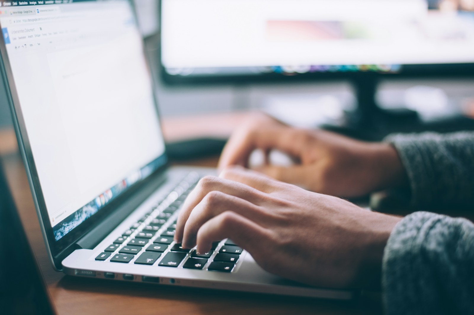 Hands typing on a laptop beside a notebook, illustrating human review after the Claude false police tip.