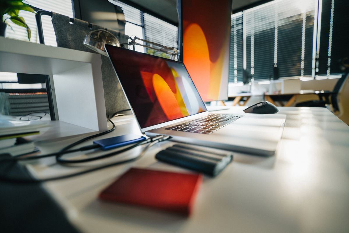 Laptop with external drives on a desk, illustrating Windows 11 24H2 support and backup preparation.