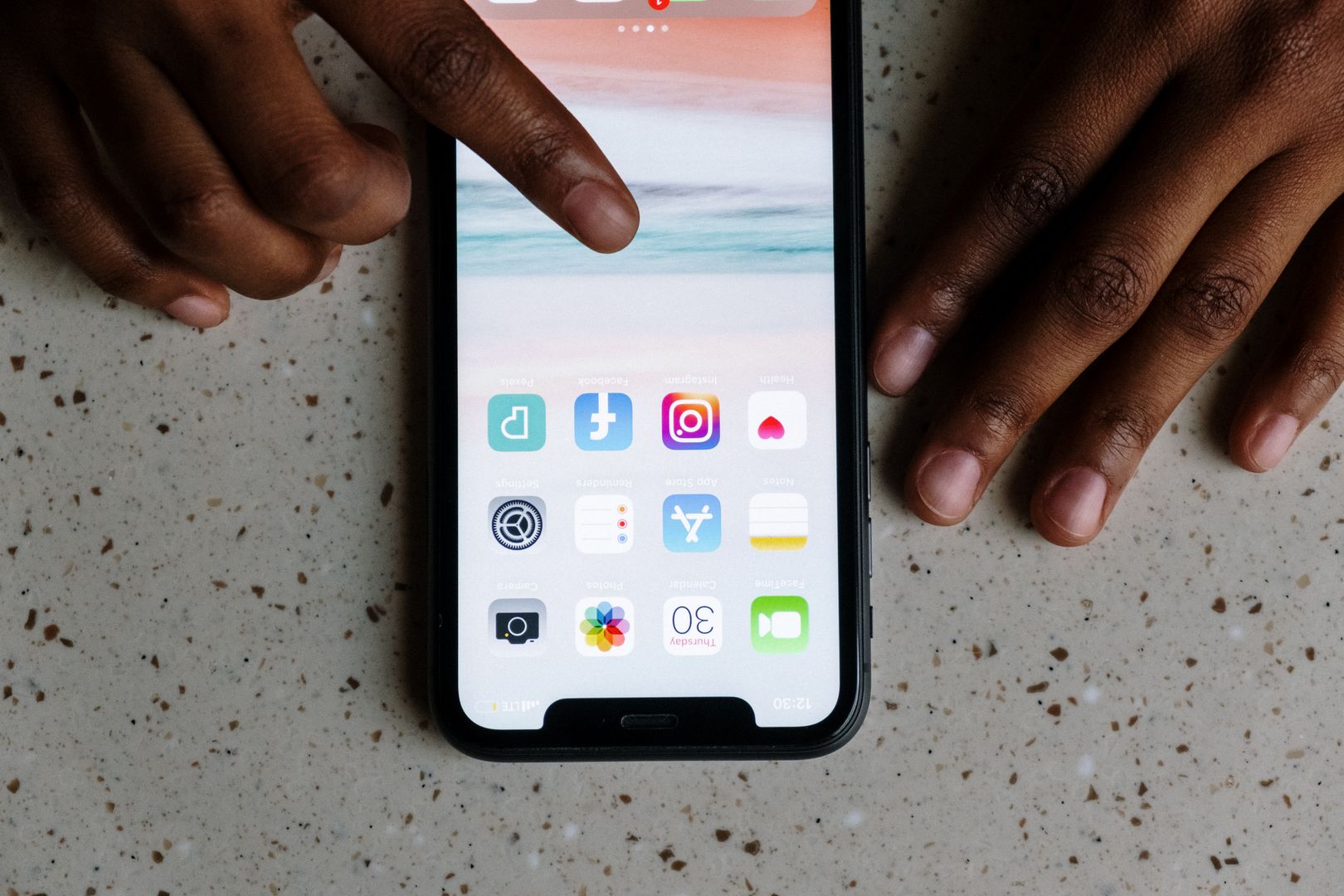 Hands using a smartphone, illustrating how zero-click ad spyware can reach a device through online advertising.